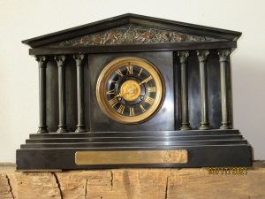An old clock sits on a mantle